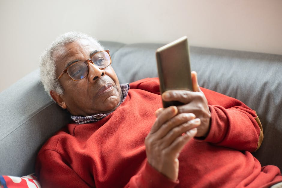 Image depicting a person using a smartphone with blue light emanating from the screen.